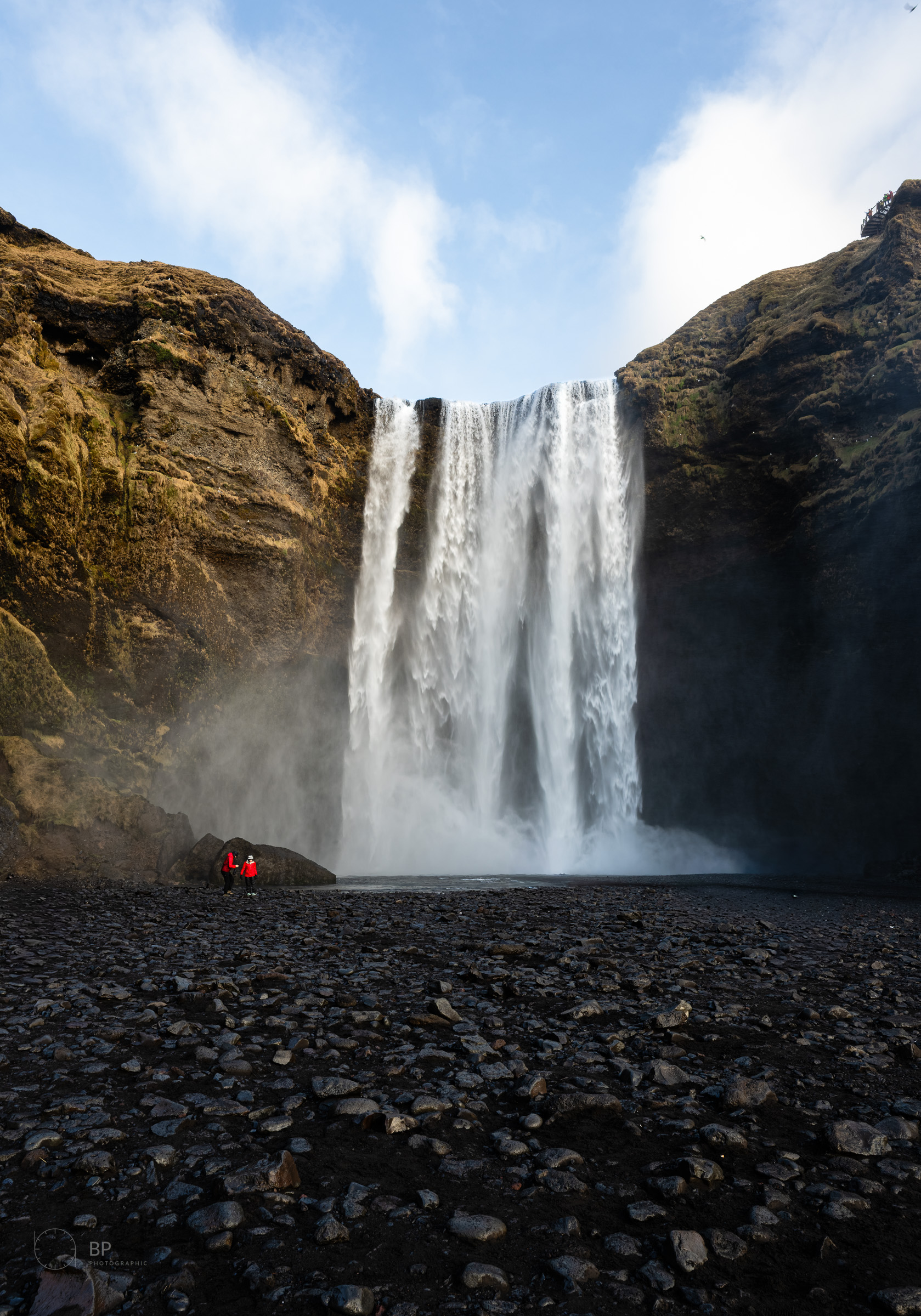 Figures dwarfed by Skógafoss
